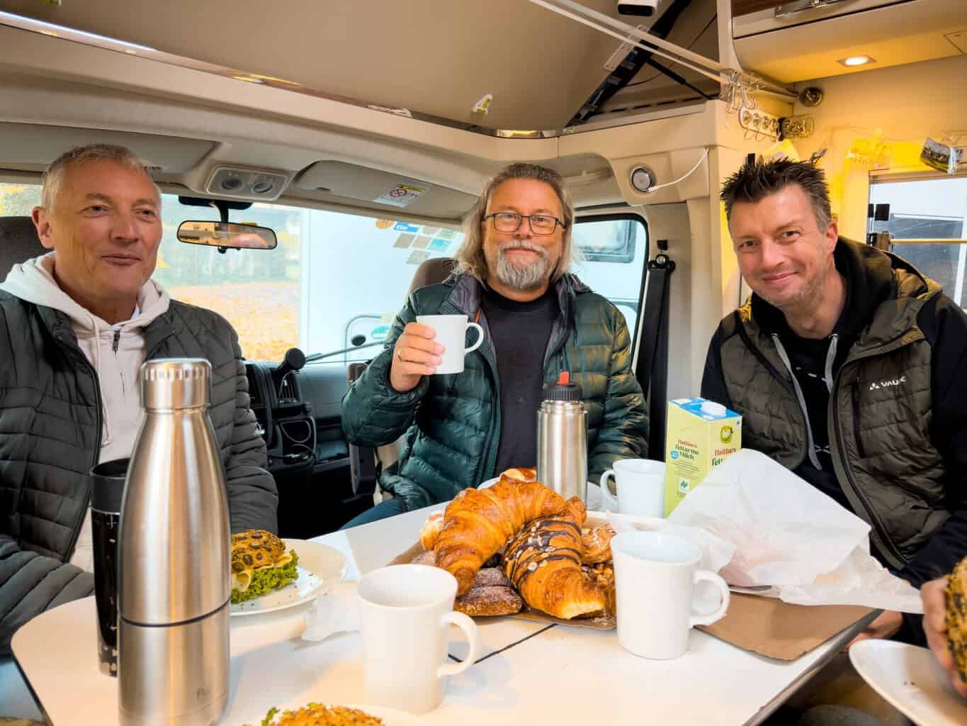 3-blickwinkel-drehtag-kaffee-und-croissants Frank, Roland und Flo mit Kaffee und Croissants am Tisch im Wohnmobil