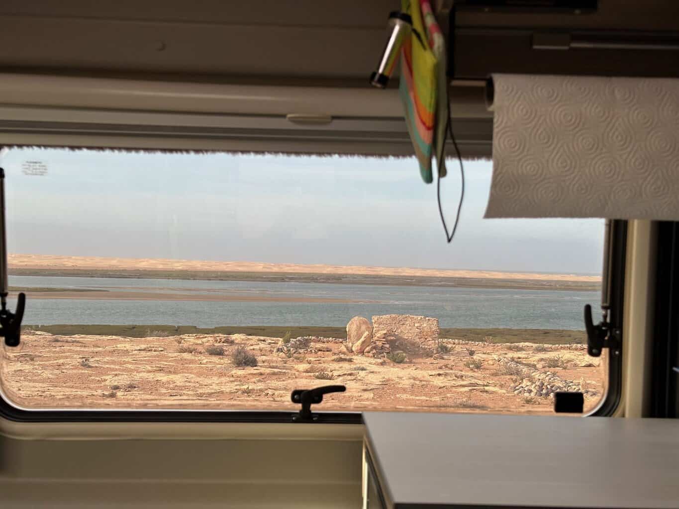 Blick aus dem Wohnmobilfenster auf Strand und Meer