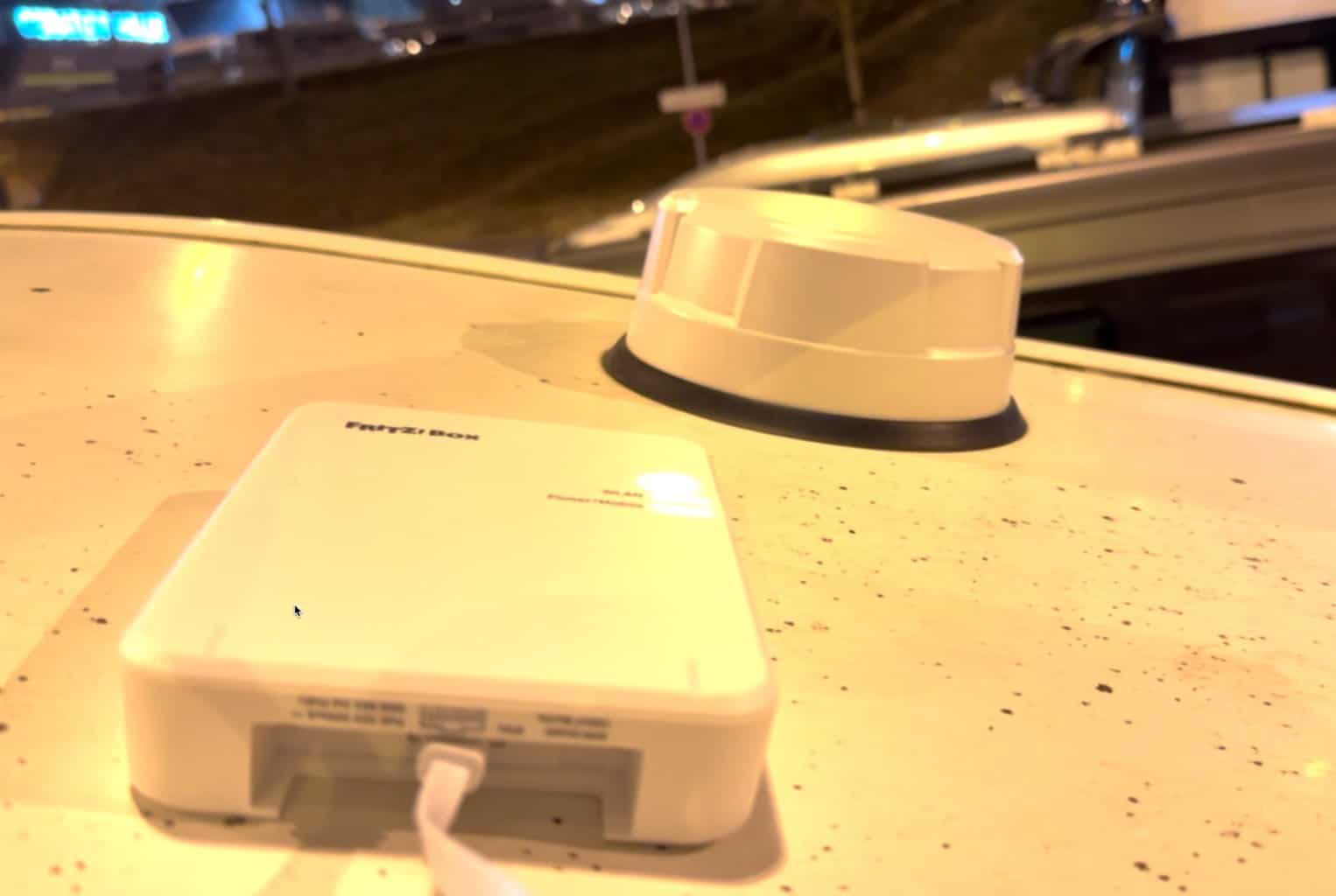 Fritzbox 6860 5G liegt abends auf dem Dach eines Wohnmobils, dahinter ein runder weißer Dachaufbau