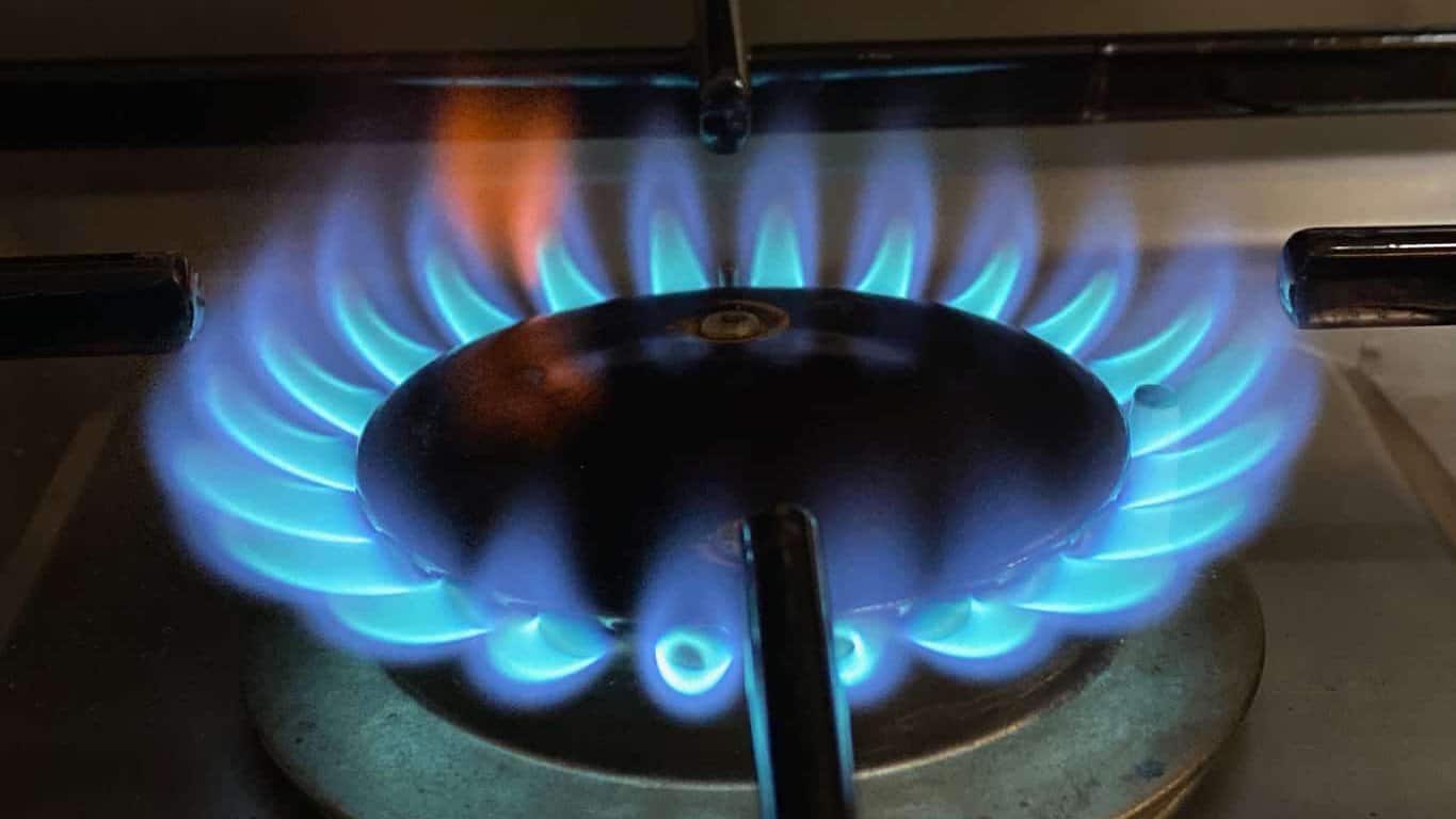 Blaue Gasflammen am Brenner eines Gasherds im Wohnmobil, einzelne Flammen mit gelber Spitze