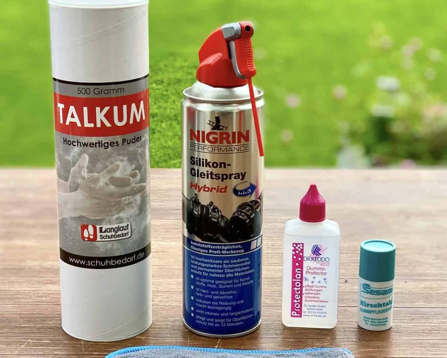 Nigrin Hybrid Silikon-Gleitspray, Spraydose auf Holztisch, daneben Talkum und Dr. Keddo Protectolan
