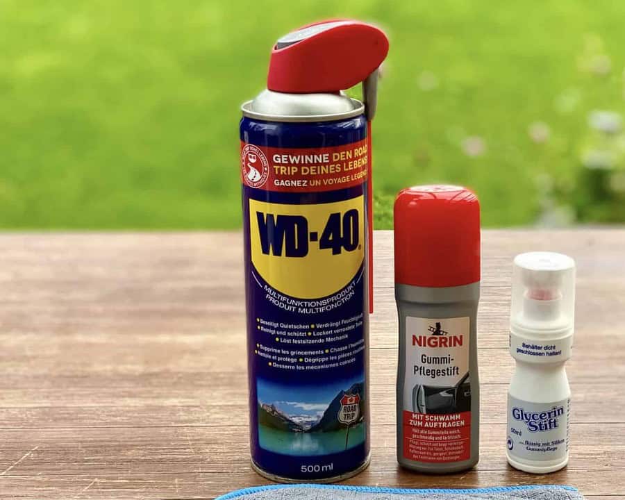 WD-40 Multifunktionsspray 500 ml auf Holztisch, daneben Nigrin Gummi-Pflegestift und Glycerin-Stift
