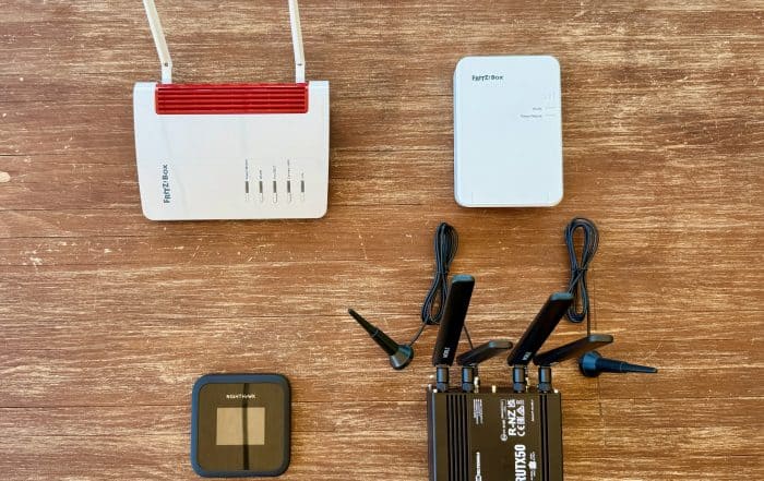 Zwei Fritzbox-Router, ein Netgear Nighthawk und ein Teltonika mit Antennen nebeneinander auf einem Holztisch