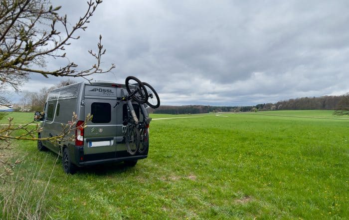 Pössl Kastenwagen auf einer Wiese mit Fahrrad auf dem PUSHrack Heckträger