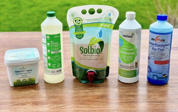 Fünf Bio-Sanitärflüssigkeiten nebeneinander: Ammovit, bio-chem, Solbio, awiwa und Klo Floh