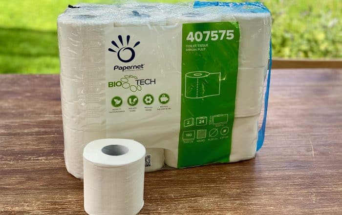 Papernet BioTech Toilettenpapier, 24er-Gebinde mit einer einzelnen Rolle davor auf einem Holztisch