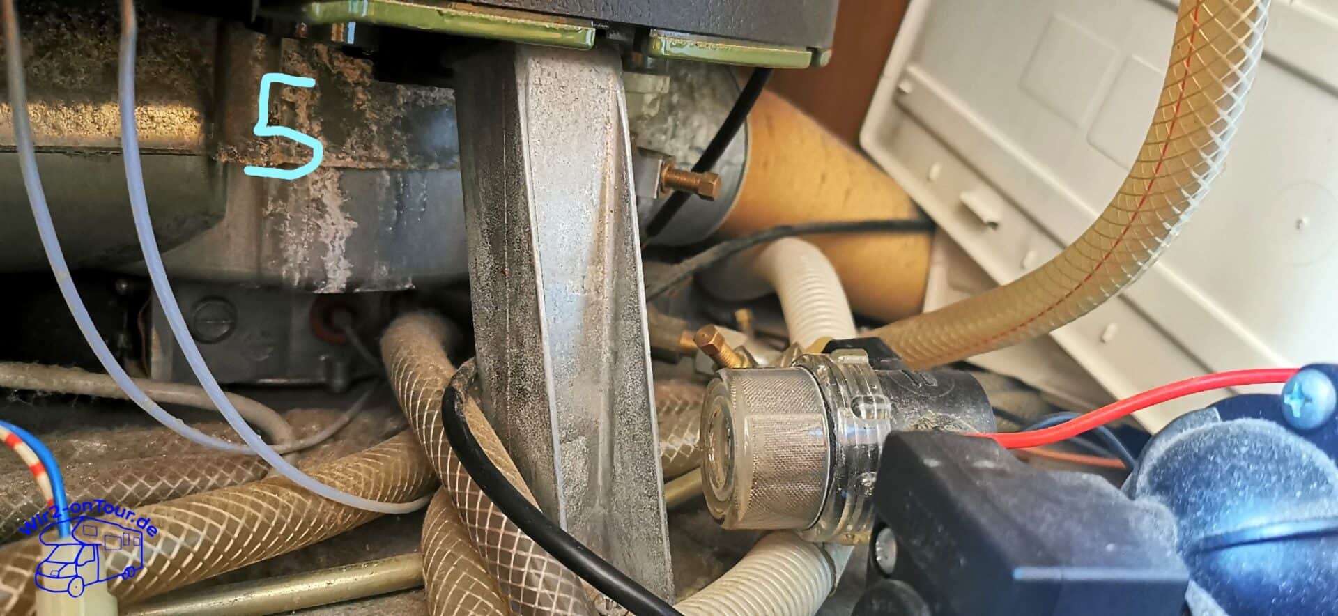 Blick unter den Boiler auf das Halteblech, gewebeverstärkte Wasserschläuche und einen Siebfilter mit Metallgewebe