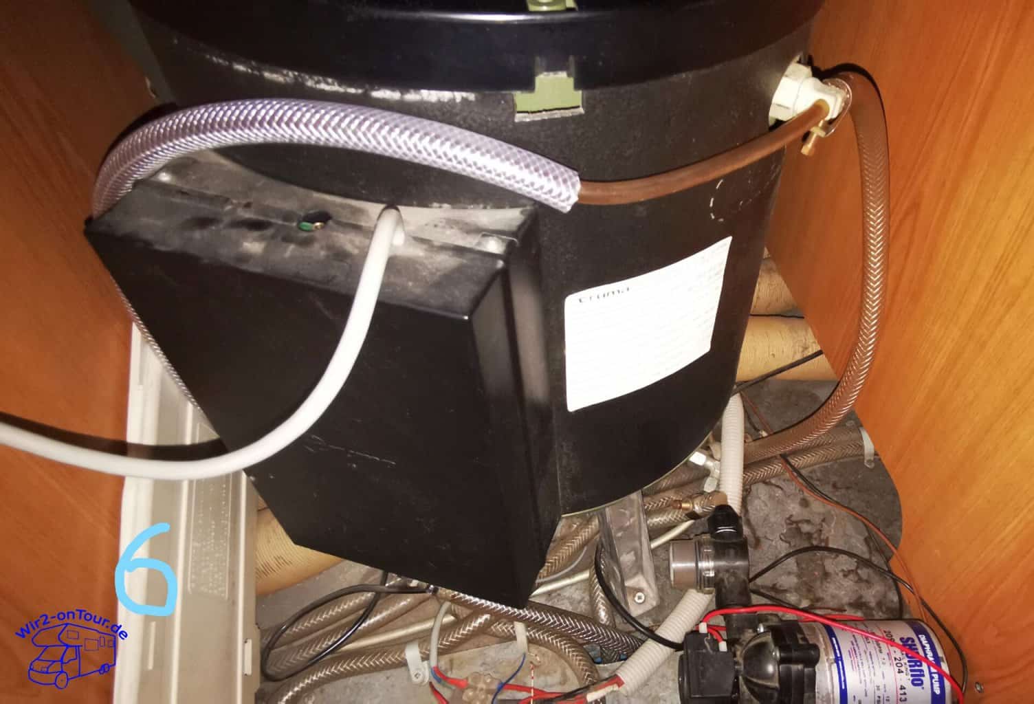 Boiler von oben mit schwarzem Steuerkasten, rechts oben das weiße Entlüftungsventil mit Schläuchen, unten die Wasserpumpe