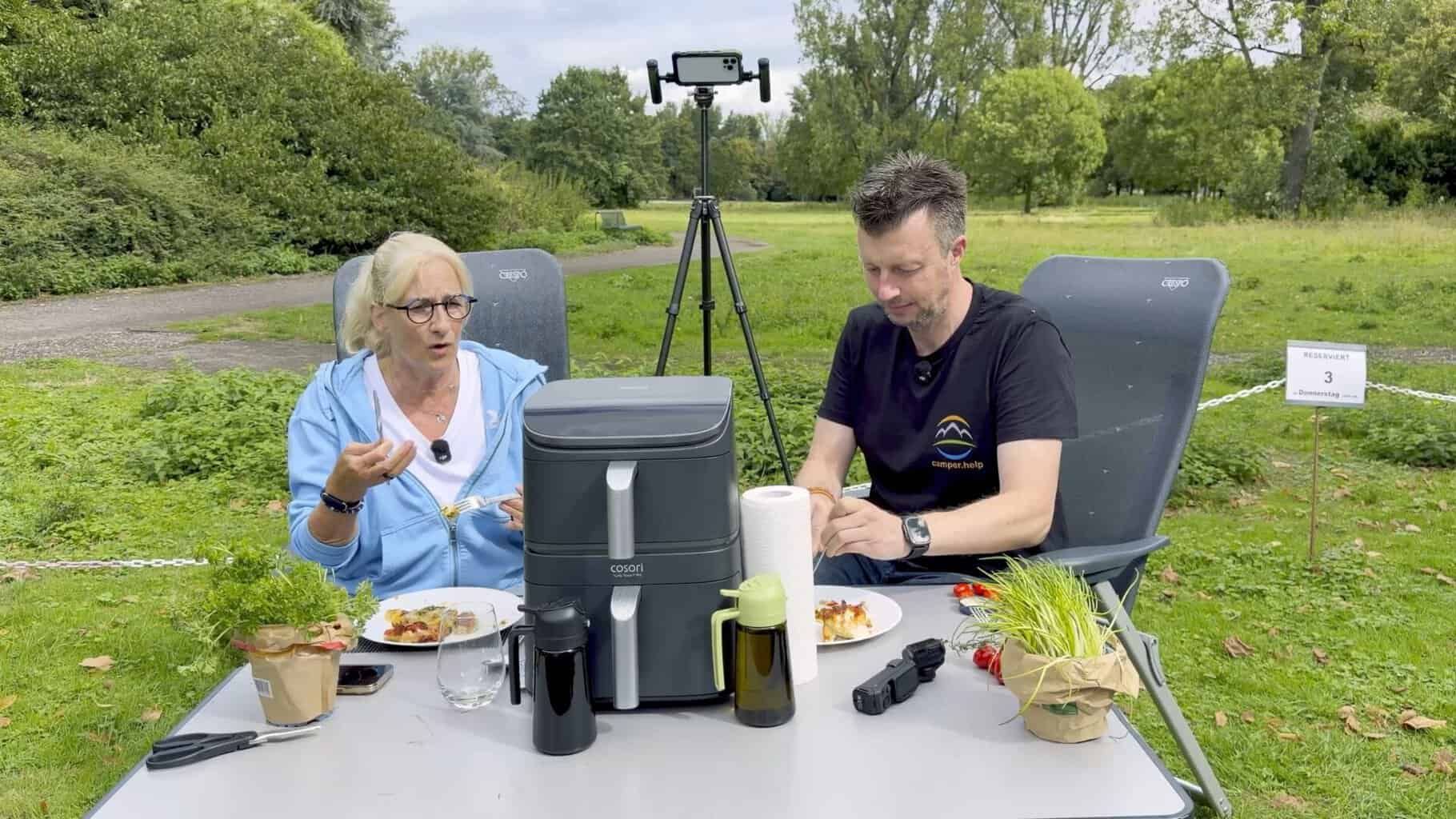 anke-und-flo-essen-am-campingtisch Anke und Flo essen am Campingtisch, zwischen ihnen der Airfryer