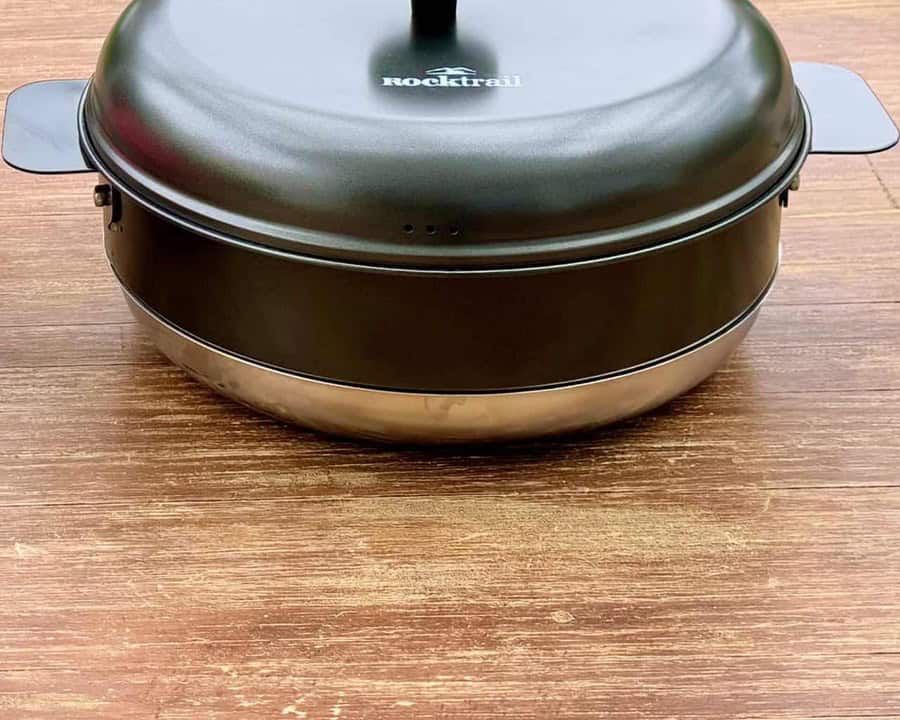 Camping-Backofen Rocktrail von Lidl mit geschlossenem dunklem Deckel und seitlichen Griffen auf einem Holztisch