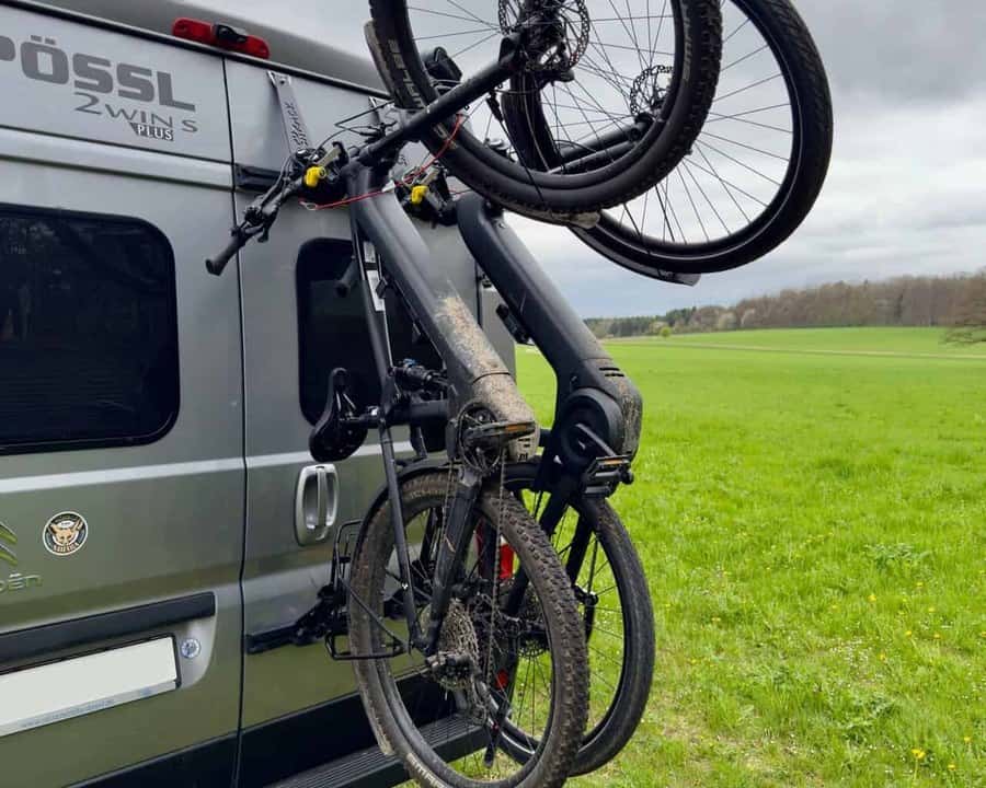 Pushrack E Bikes montiert gross (Box 5:4) E-Bikes am PUSHrack-Träger an der Hecktür eines Pössl-Kastenwagens vor einer Wiese